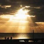 Golden rays shining through dark clouds to represent the good news of Jesus in a war-torn world