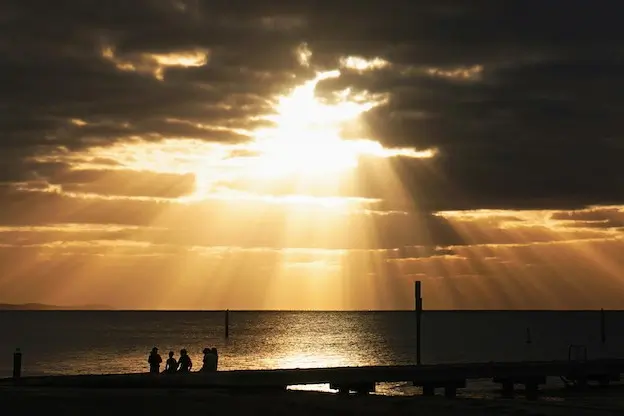 Golden rays shining through dark clouds to represent the good news of Jesus in a war-torn world